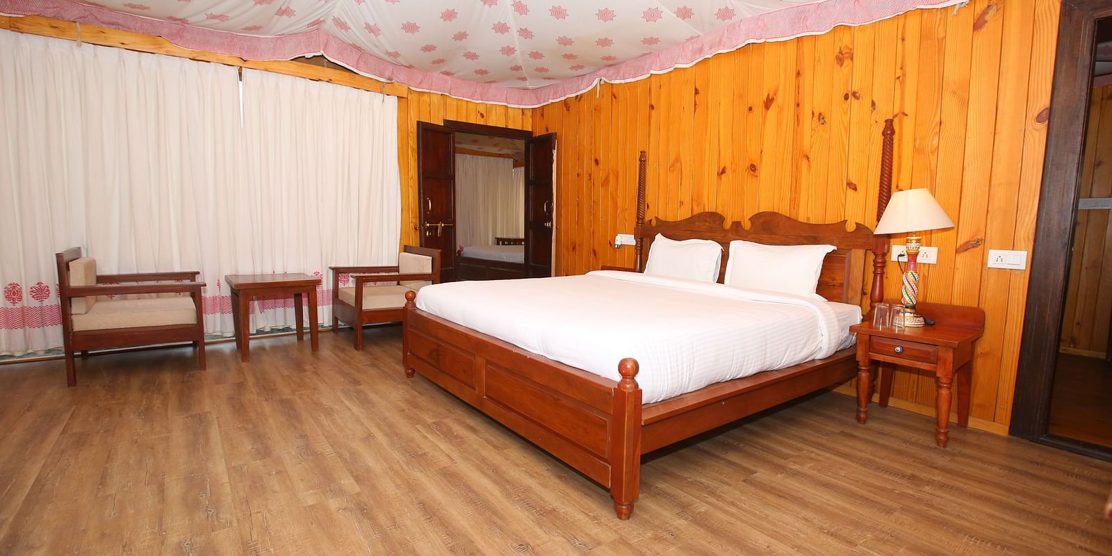 Luxury Wooden Tent featuring a king-sized bed, comfortable chairs, and stools at Aanandam Resort & Spa