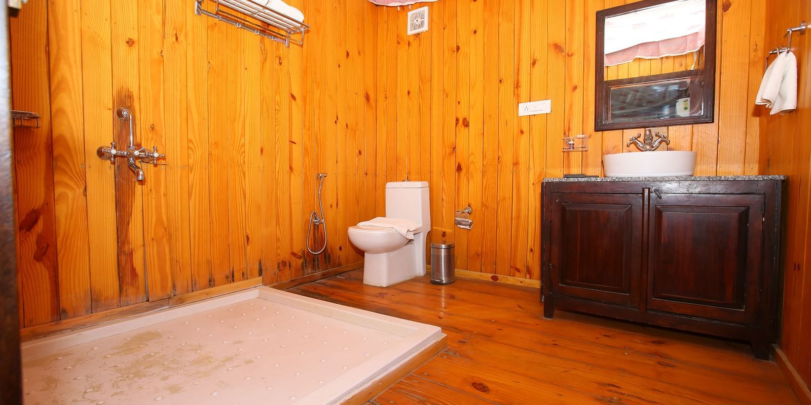 Luxury Wooden Tent washroom with a sleek sink, a separate bathing area, and elegant wooden flooring at Aanandam Resort & Spa