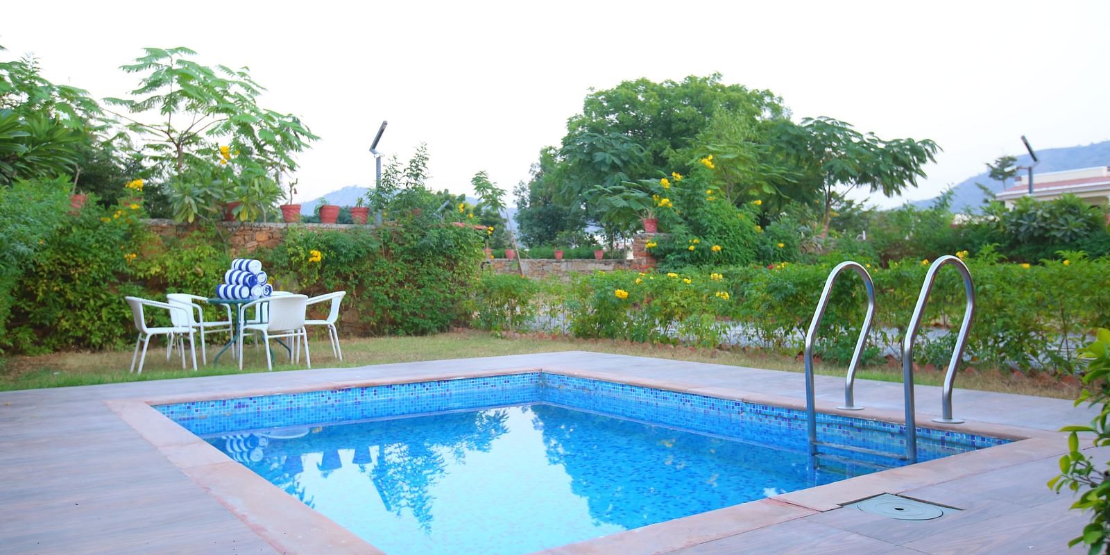 Outdoor swimming pool in front of the villa, with an open top to the clear sky and chairs arranged infront