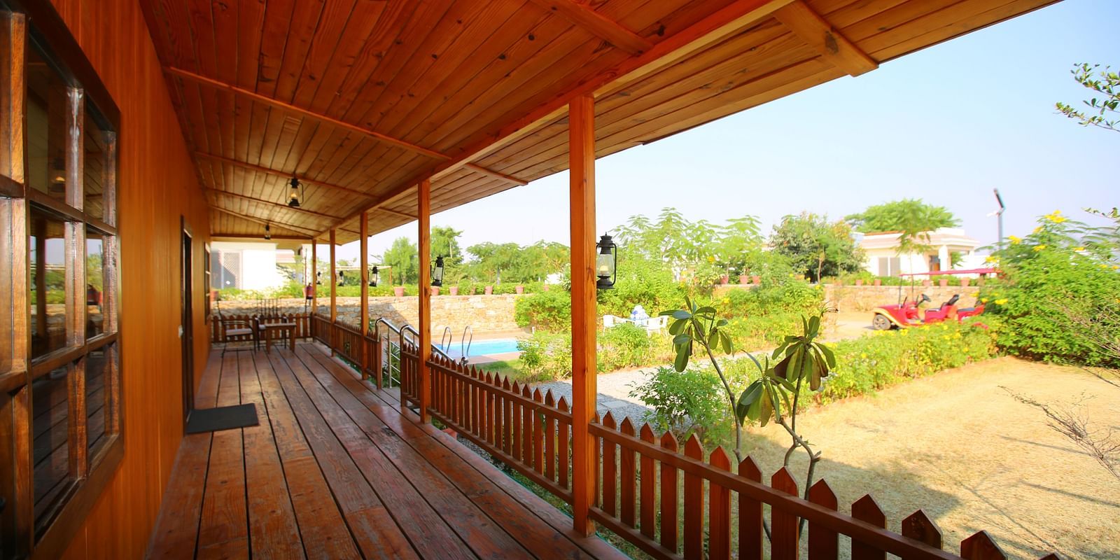Balcony of Kashmir Cottage Villa's Pool room offering a serene view of the garden at Aanandam Resort & Spa