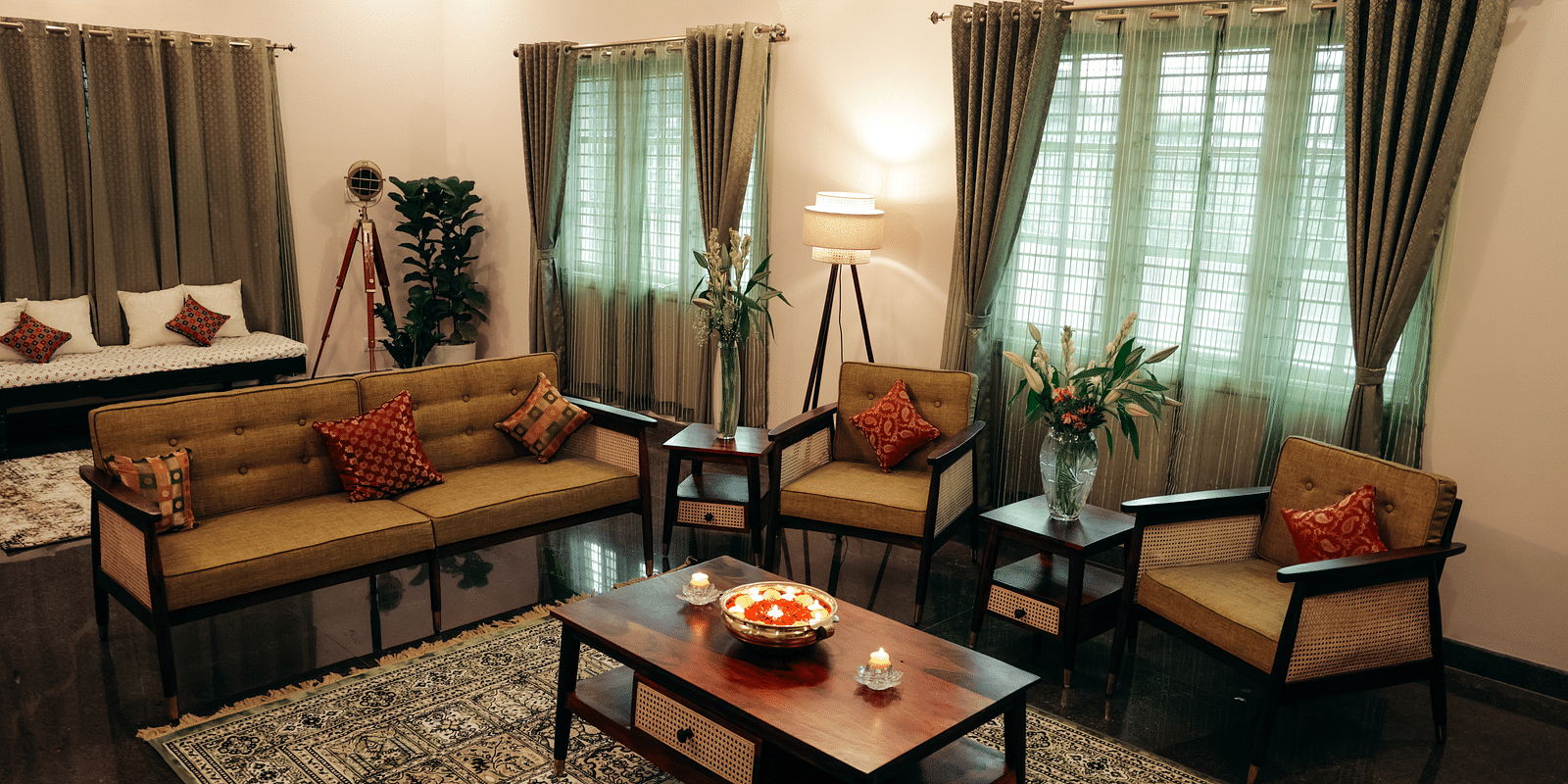 A living room with a brown sofa, two armchairs, a coffee table, and curtains on large windows | Adhyaya Heritage Reverbed