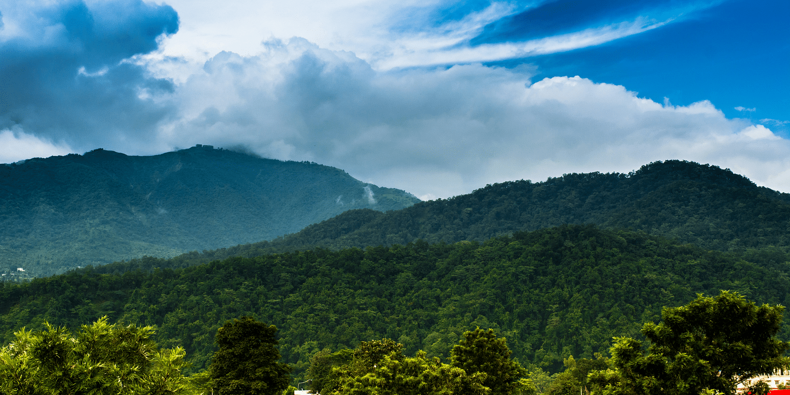 A wide view of mountains with a sky with scattered clouds in the background