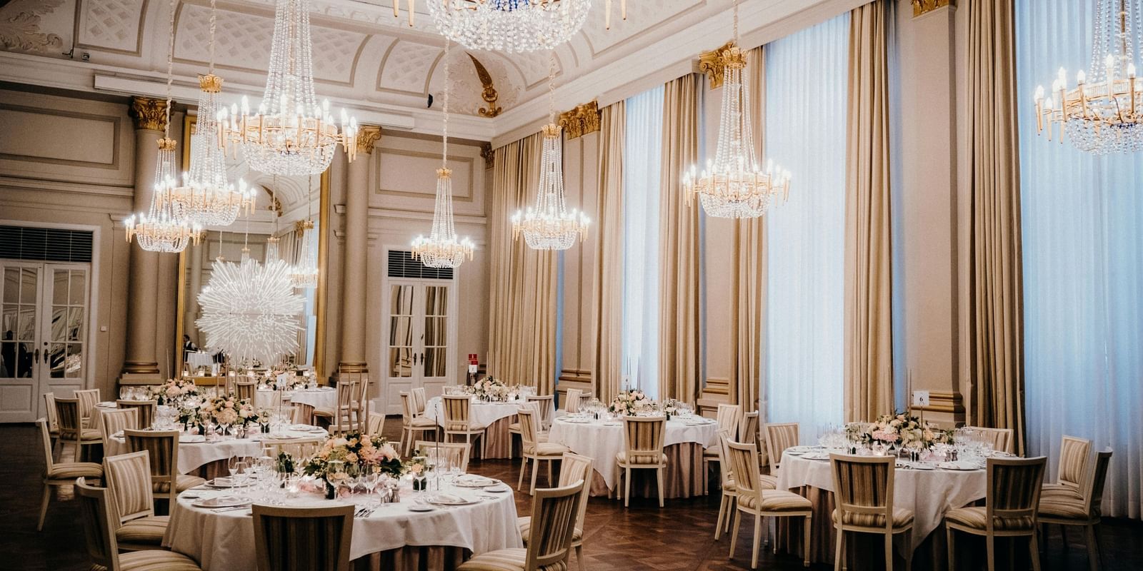 View of a lavish ballroom, tables adorned with linens and elegant decor