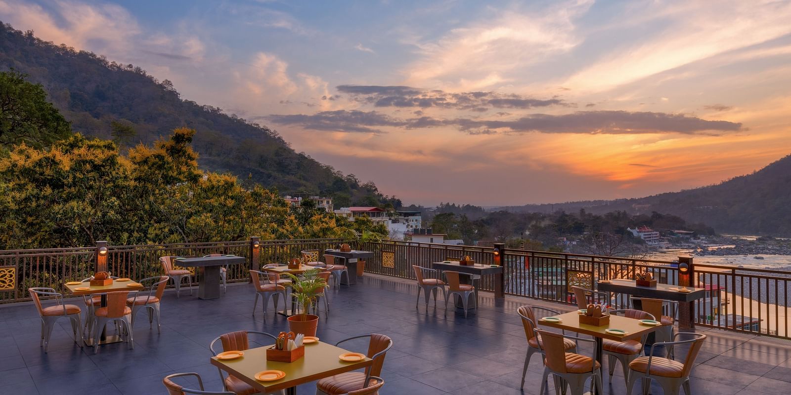 A cluster arrangement with tables and chairs on a terrace with mountain views during the sunset - Bedzzz, Rishikesh
