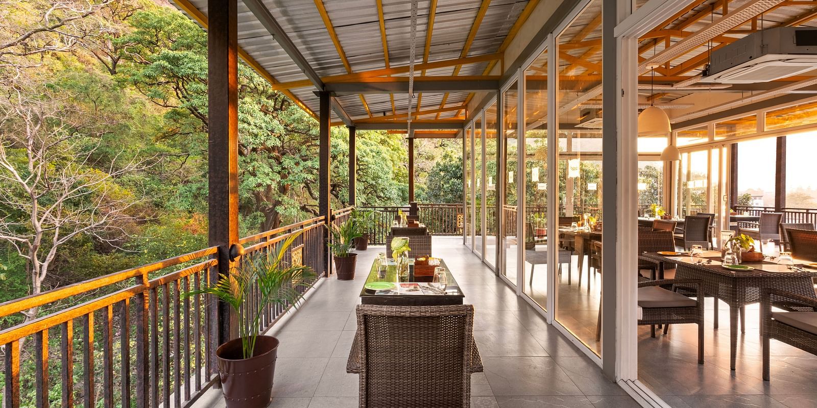 Balcony dining scene overlooking lush forest, with table set and chairs at Bedzzz, Rishikesh