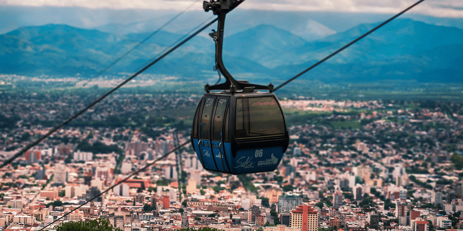 An image a cable car riding on a cable with a backdrop image of a city line - Bedzzz Xclusiv Ikshana Luxe, Nainital