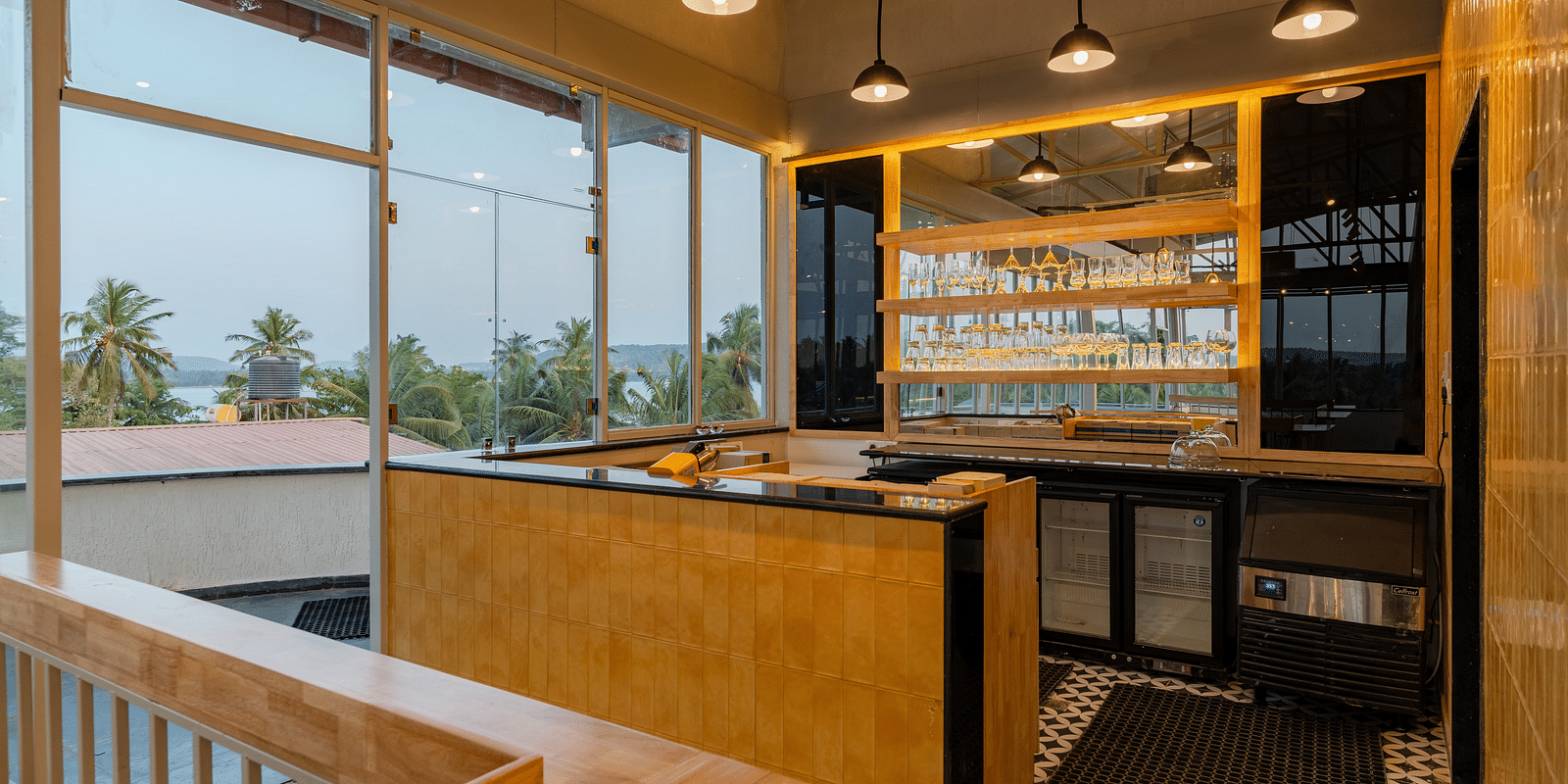An elegant bar area with a wooden counter and backlit shelves, creating a sophisticated space for guests to enjoy a selection of fine wines and spirits in a modern, yet cosy ambiance  at Bedzzz Xclusiv Morjim, Goa