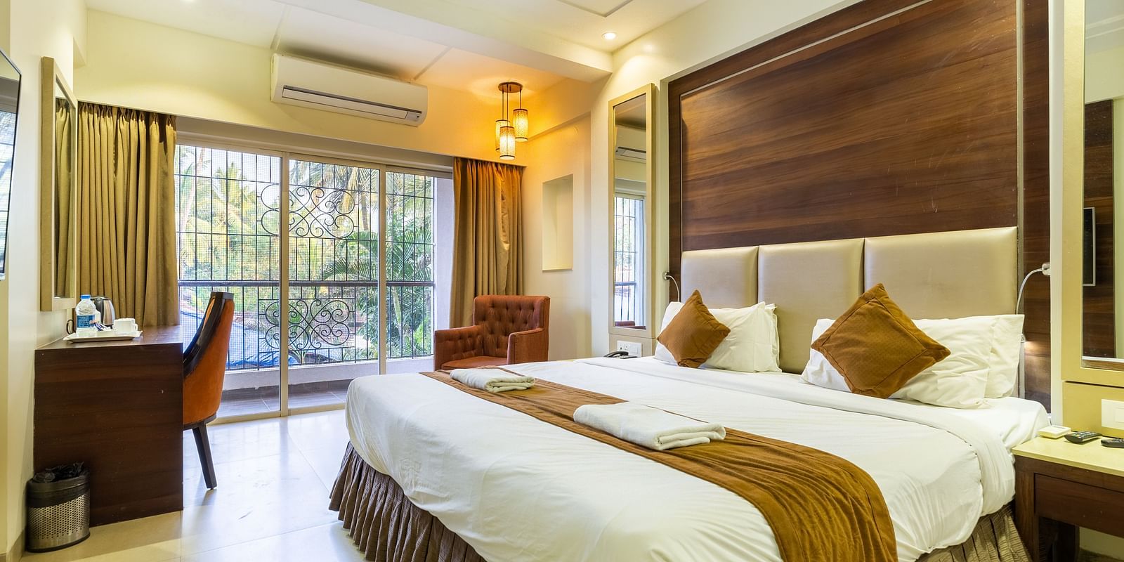 Image of a room with a bed and a table with a chair in the corner at Calux Grand Inn, Calangute.