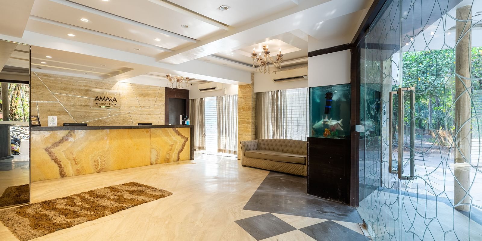 Image of a lobby area with a reception table and large glass doors at Calux Grand Inn, Calangute.