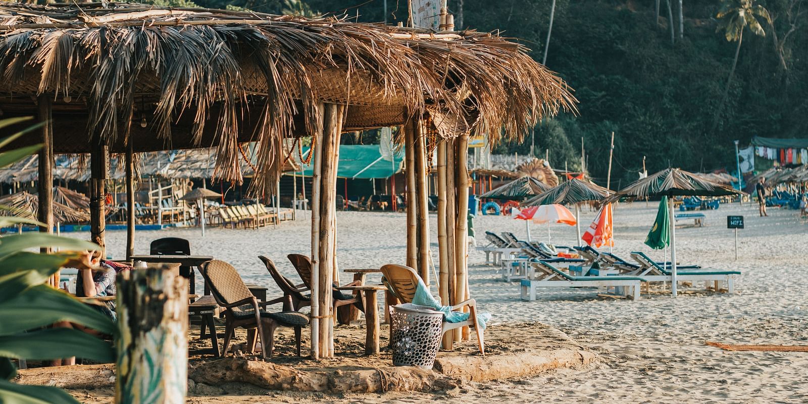 A rustic beach hut with lounge chairs on a sandy shore, offering a relaxed and tropical seaside ambiance.