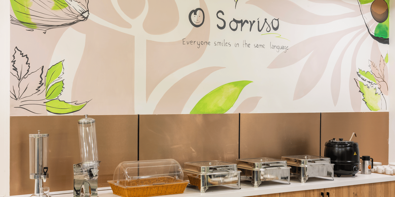 A buffet area with food warmers and a wall graphic at Elysium Studio Suites, Madhapur, shows food service equipment.