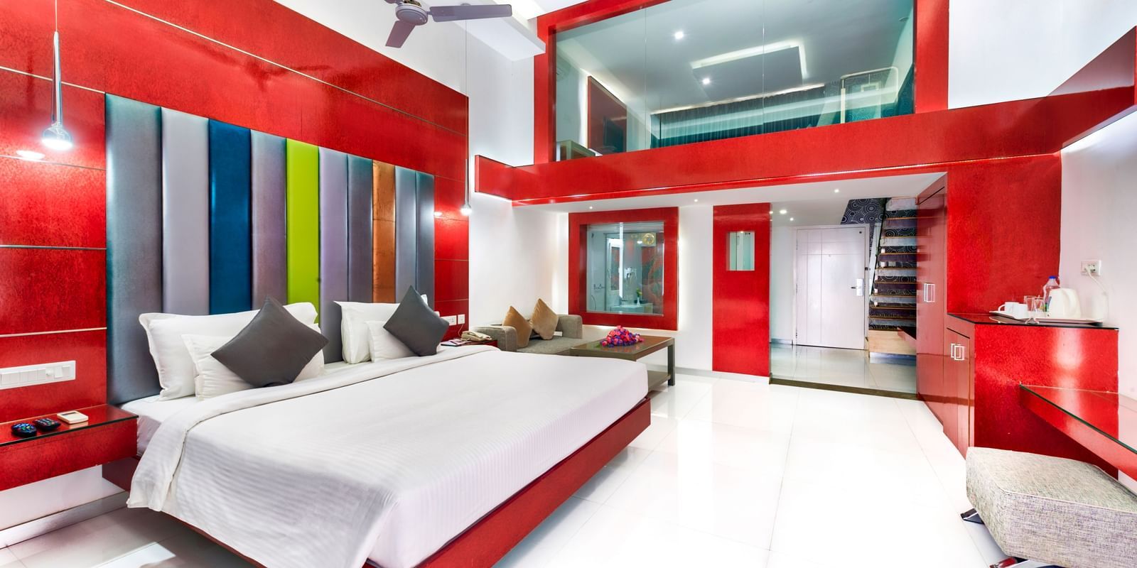 A room with a king size bed, colourful headboard, red and white decor, and seating area at Grande Bay Resort & Spa