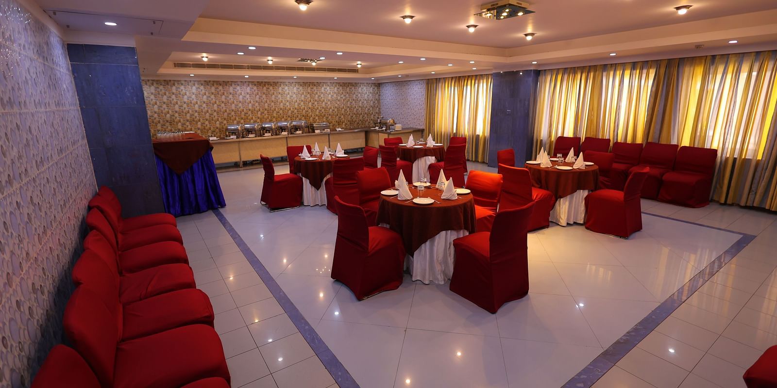 Overview image of Dewaane-e-khas hall of Hotel Amar with red chairs and cluster seating arrangement 