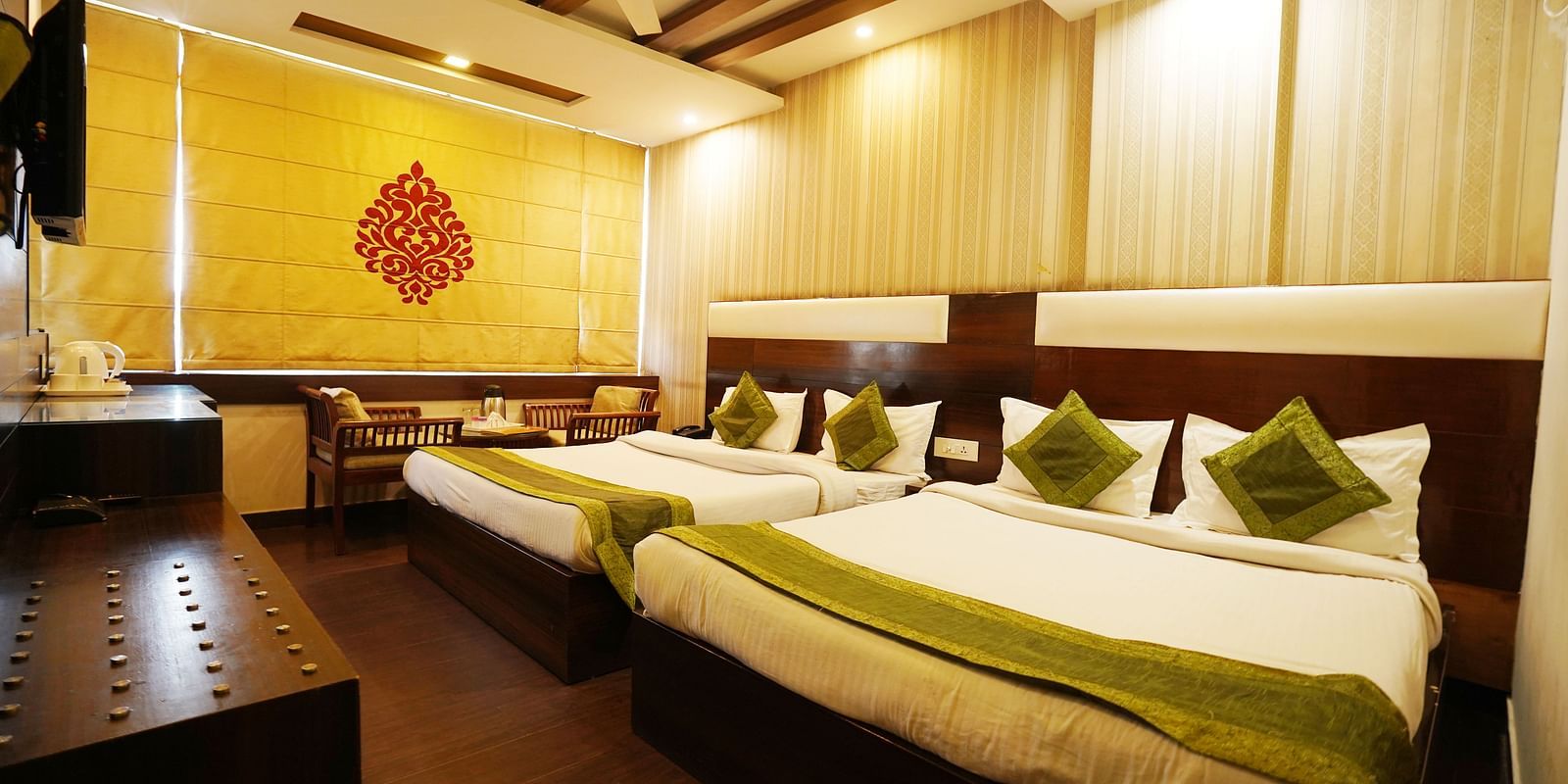 Family Room featuring two large king size beds with green accents, a wooden floor, and warm lighting. 