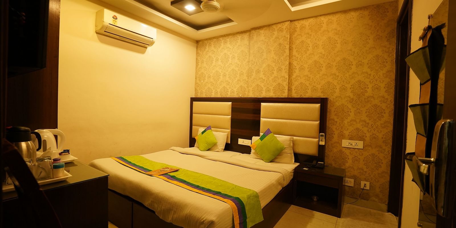 Standard Room featuring a double bed with green accents, a bedside table, and an air conditioning unit. - Hotel Dreamland, Chandigarh