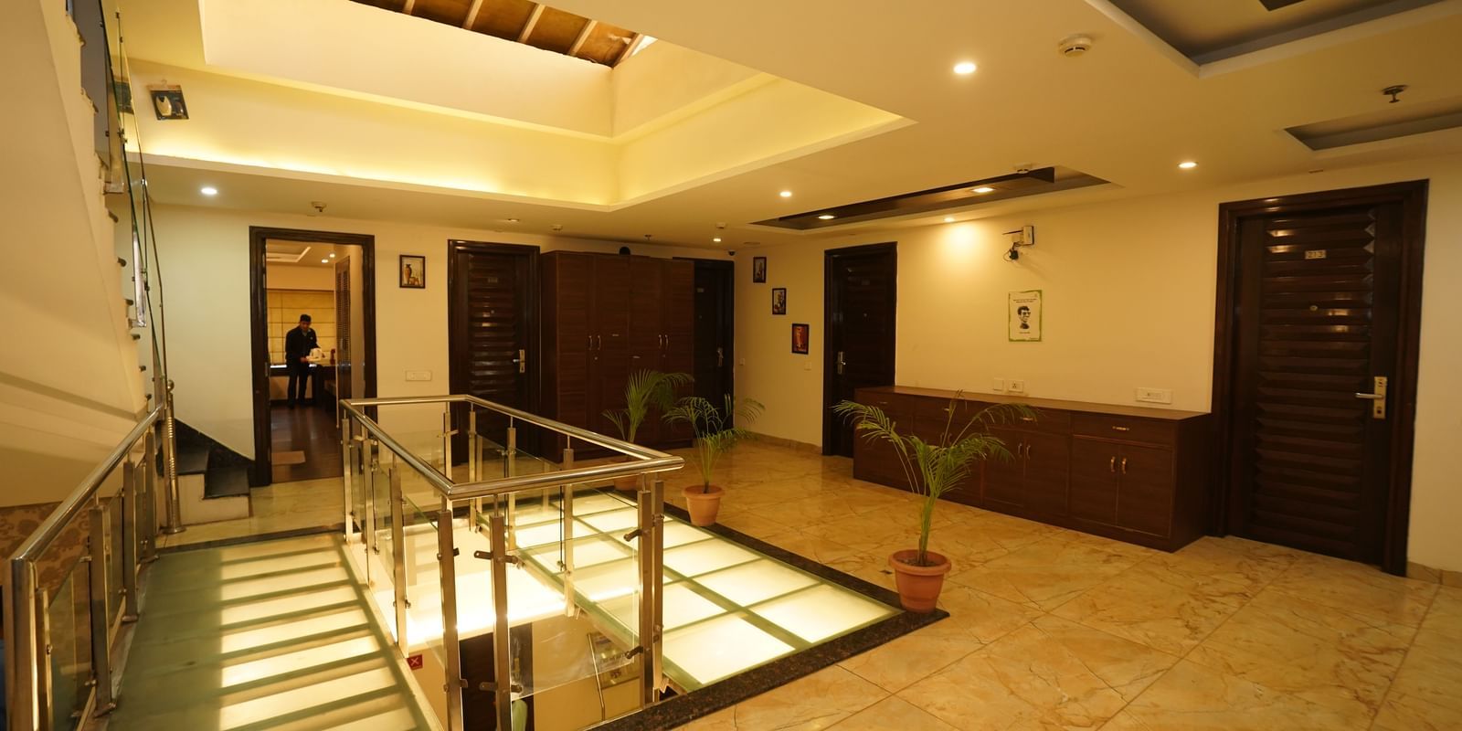 A man carrying a tray inside a room seen from lobby area, with multiple doorways, in Hotel Dreamland, Chandigarh