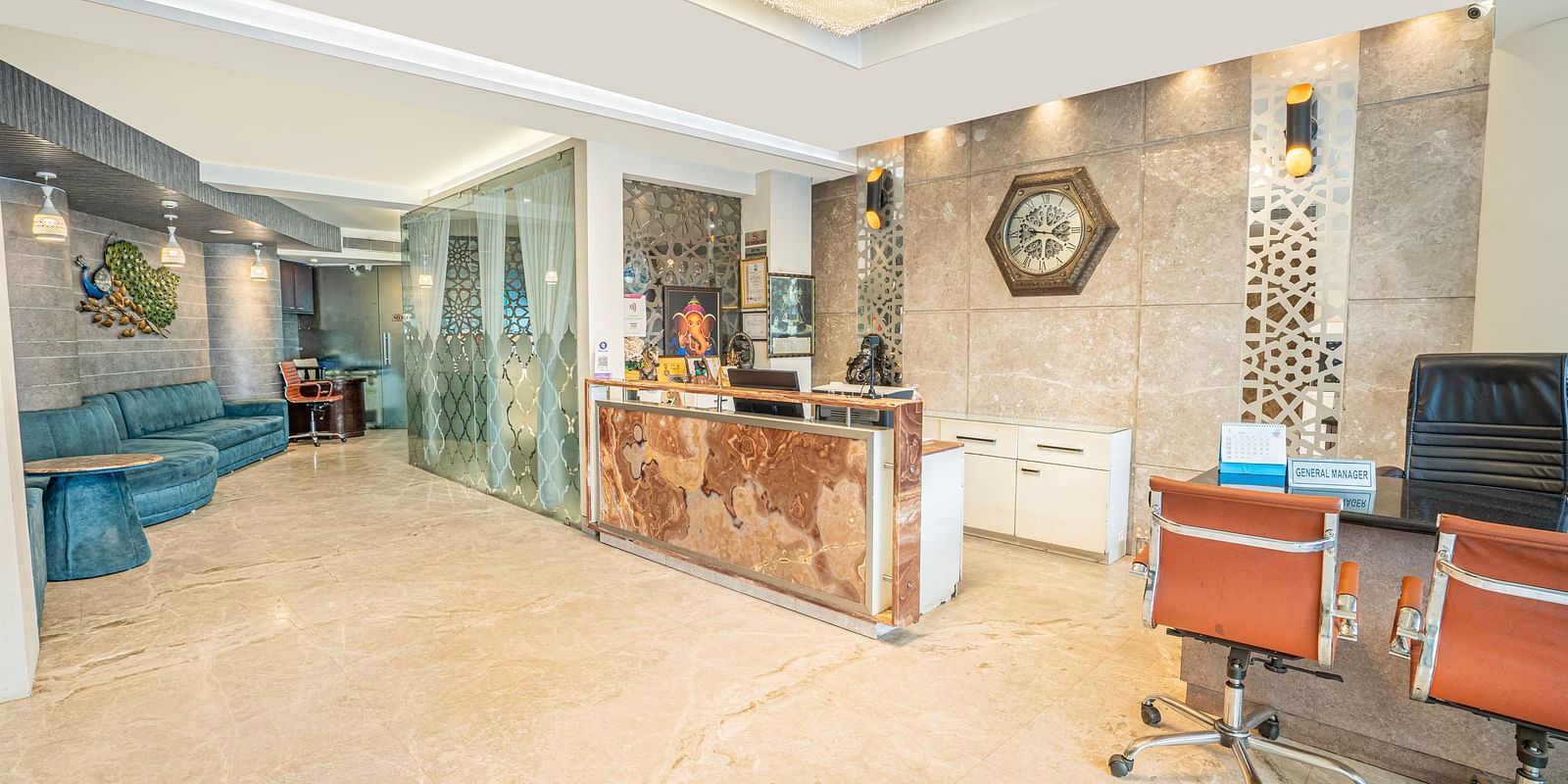 The reception area at Hotel Moti Palace, featuring a help desk and a comfy sofa for guests.