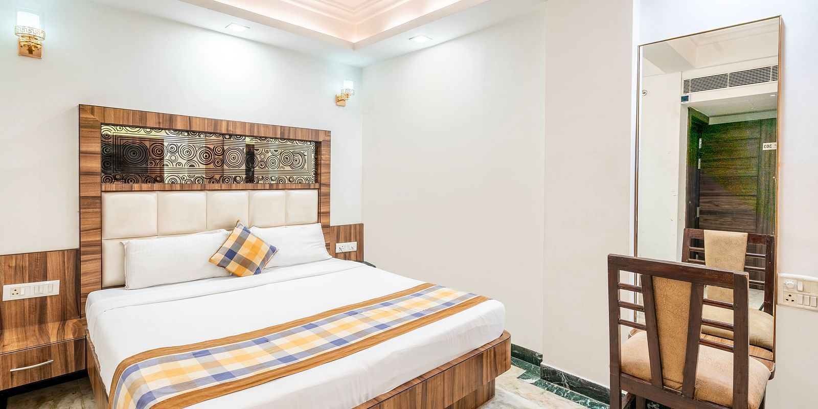 A side angle view of the bedroom at Hotel Moti Palace, featuring a comfy bed and a dressing table.
