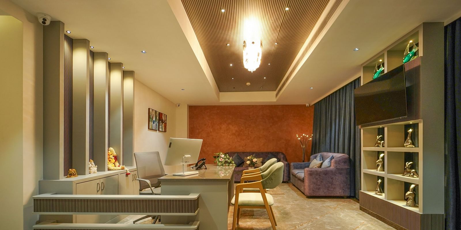 A room features a desk area with a computer, seating including a sofa and chairs, shelving with a television, and window coverings - Hotel Park Inn, Nellore.