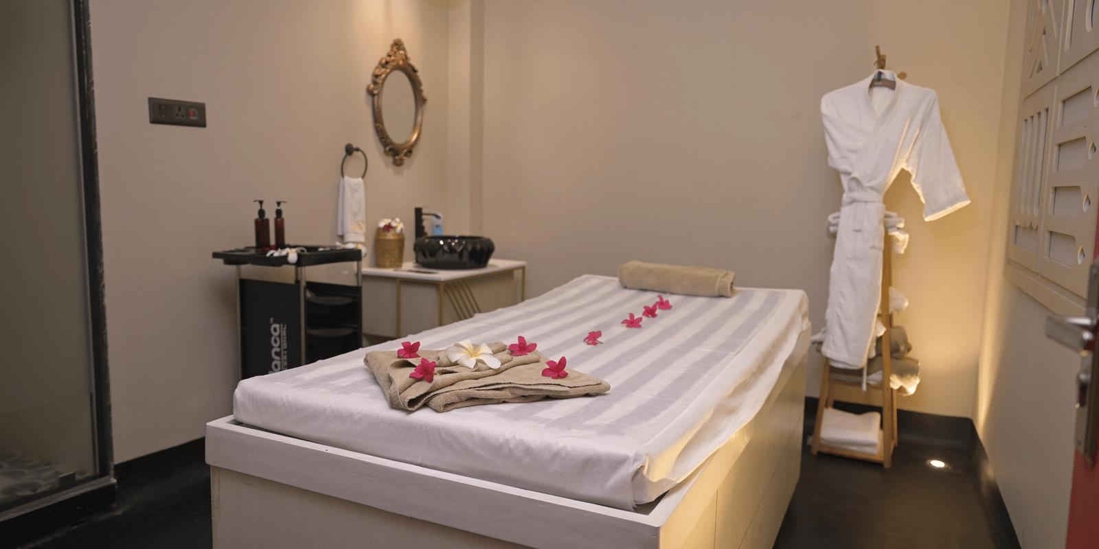A spa room with a neatly arranged massage bed and treatment essentials at Hotel Sonar Bangla Mayapur.