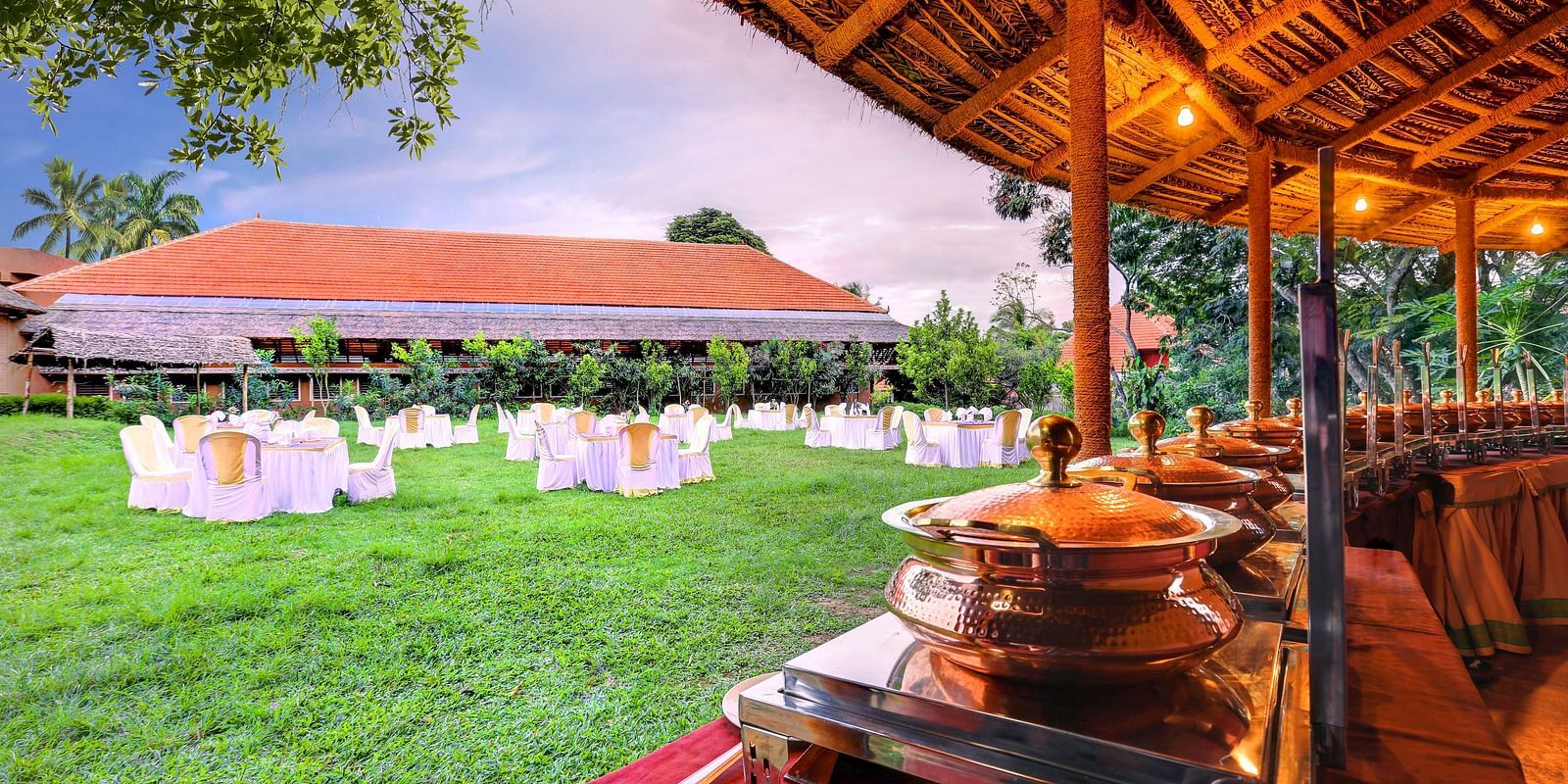 An overview of the lawn area as seen from the restaurant with elaborate seating arrangements at hoysala village resort.