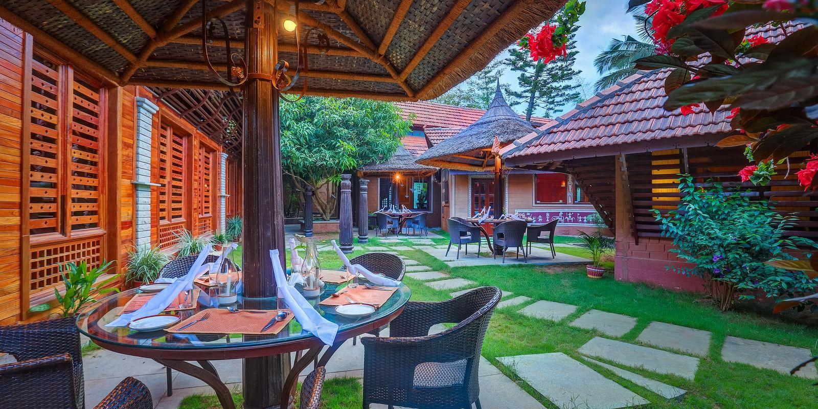 image of the open garden dining area with beautiful serene backdrop of exotic flora at hoysala village resort, hassan
