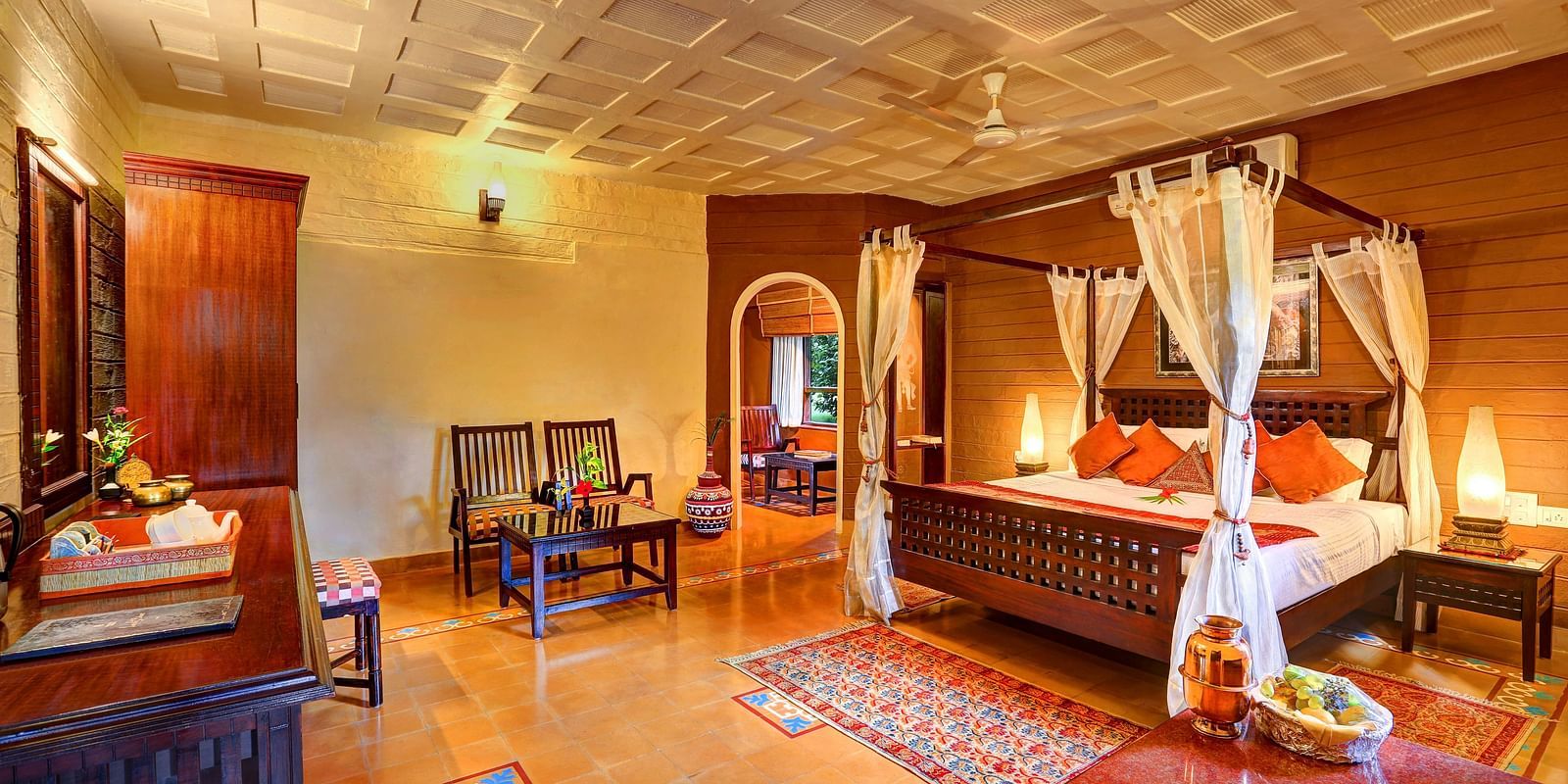 An image of a bedroom with seating area, open windows, lamp, dressing table, etc. -  Hoysala Village Resort, Hassan.