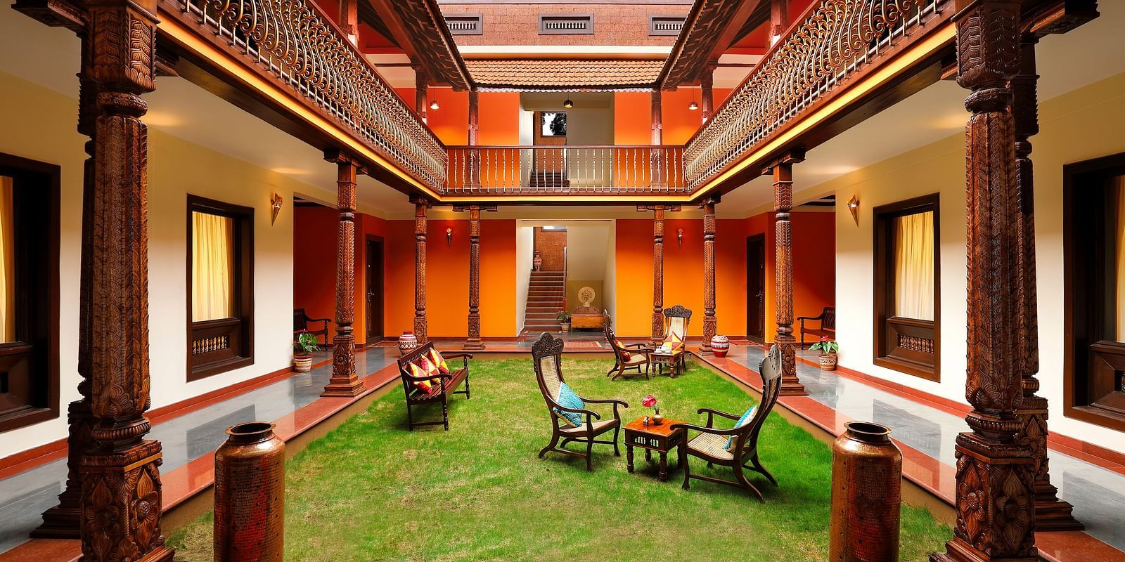 An image of a courtyard in the middle of a property where many table and chairs are kept - Hoysala Village Resort, Hassan