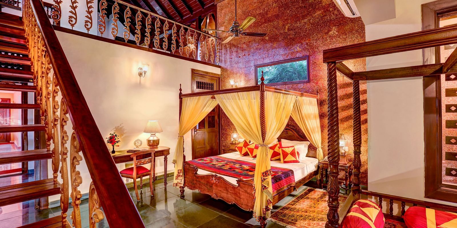 An image of a bedroom with two poster beds and a wooden stair leading to the attic of the room - Hoysala Village Resort, Hassan