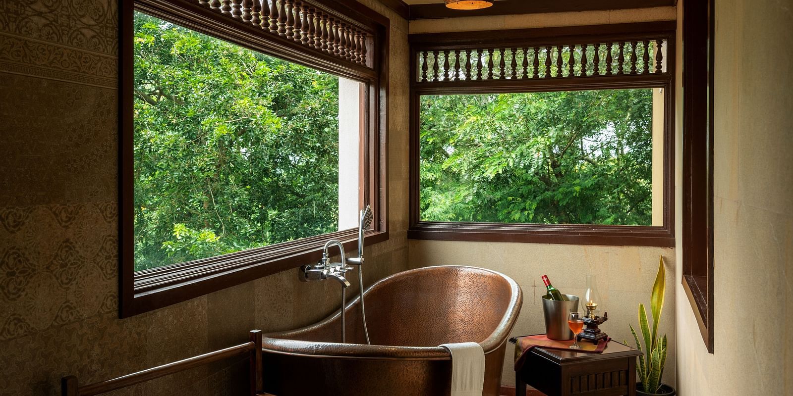 image of a copper bathtub with large glass windows at side at malnad attic suite -hoysala village resort, hassan