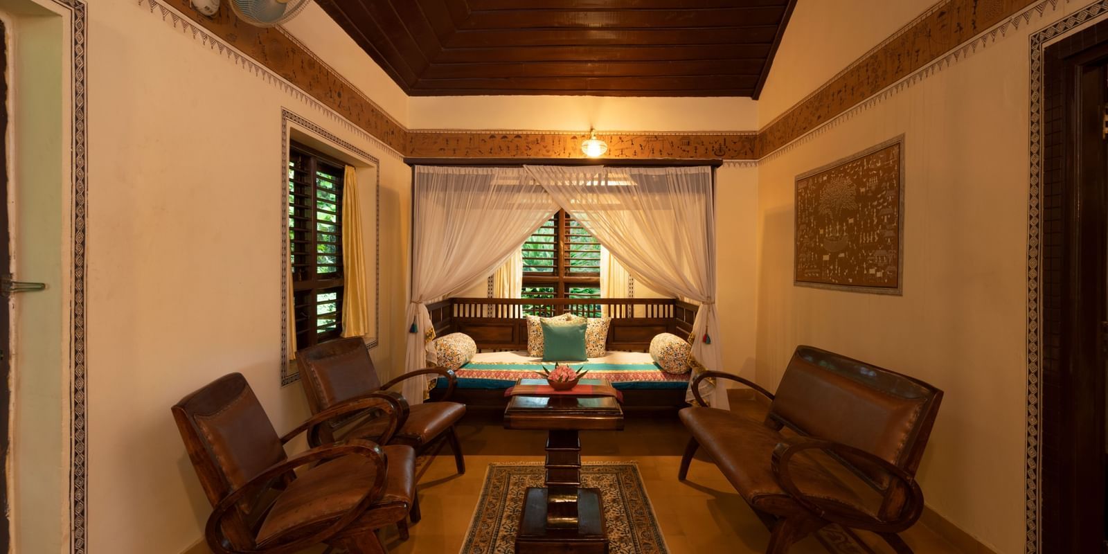 An image of a seating area which has wooden chairs and tables - Hoysala Village Resort, Hassan