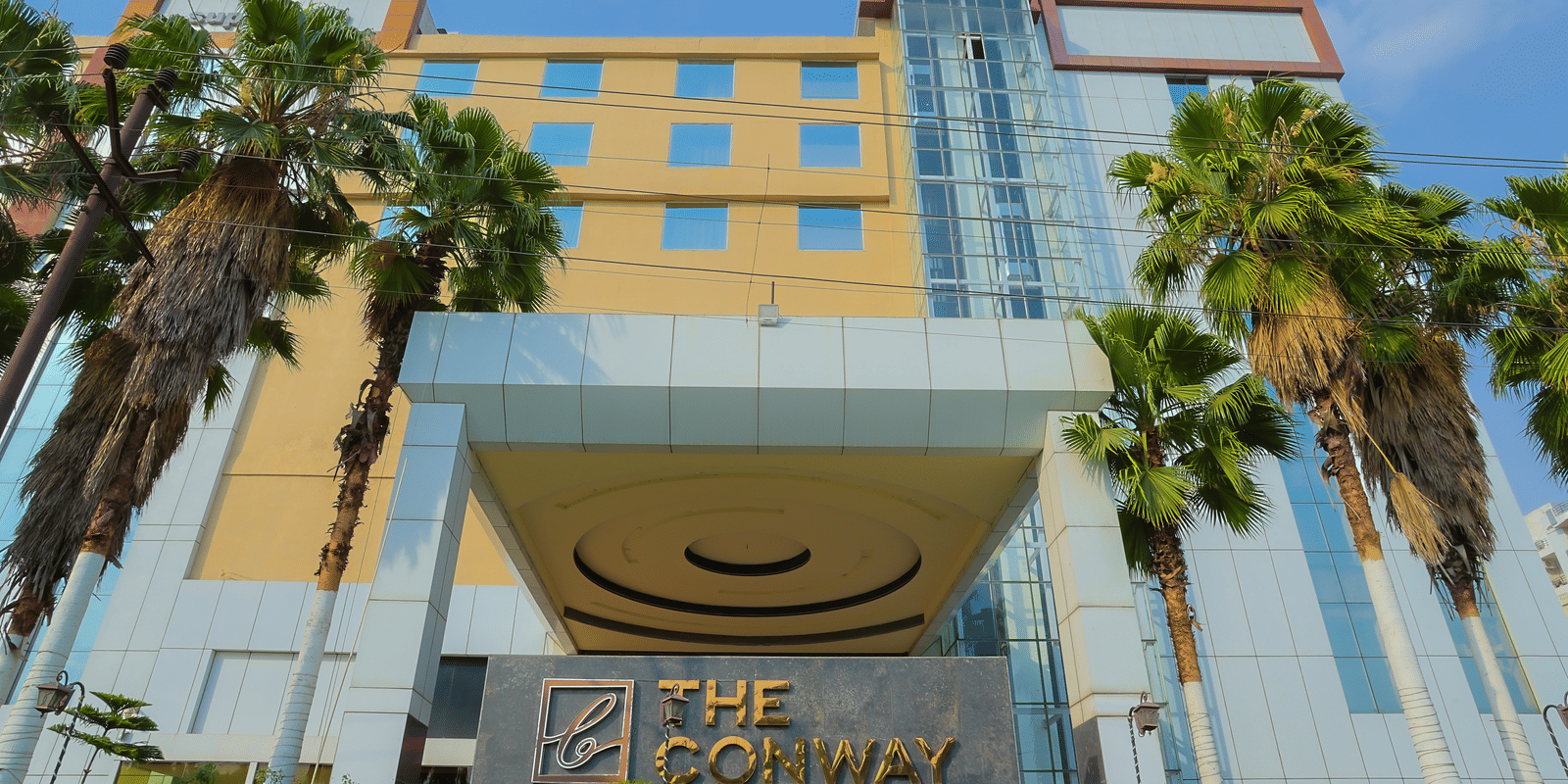 The exterior of a multi-storey hotel building with a modern facade with a signage and clear sky.