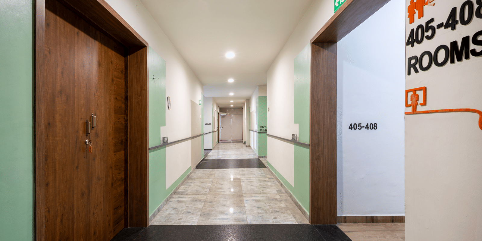 Well-lit corridor of Kove Smart Stays offering a view of multiple doorways to inner rooms & apartments.