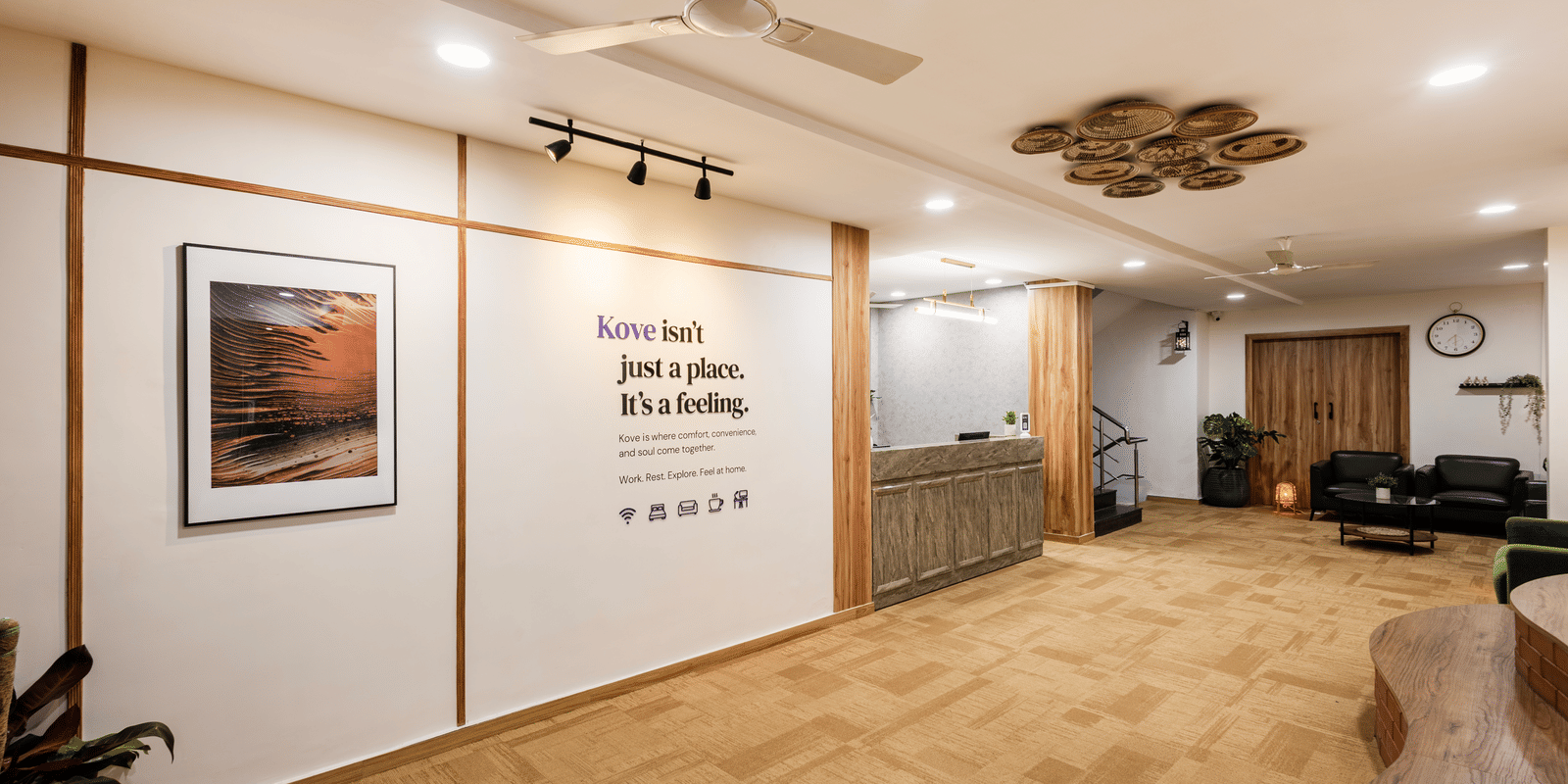 Lobby, entryway, and reception desk of Kove Smart Stays featuring wooden interiors, ample lighting, & signage of a quote on the wall.