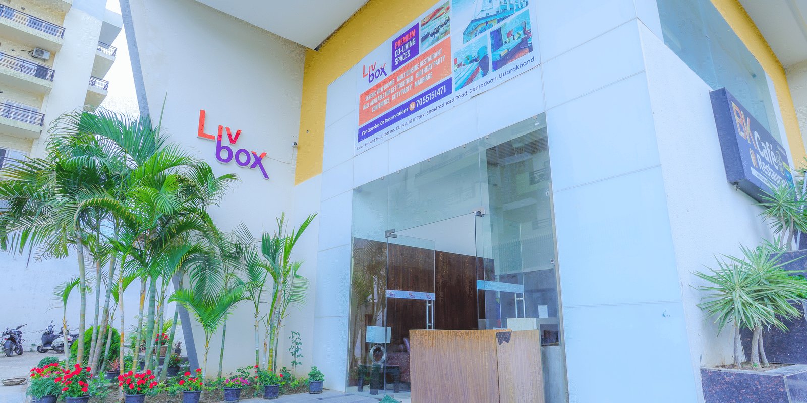 The facade of Livbox, Dehradun, featuring a large entrance, potted plants placed ahead of the entrance.