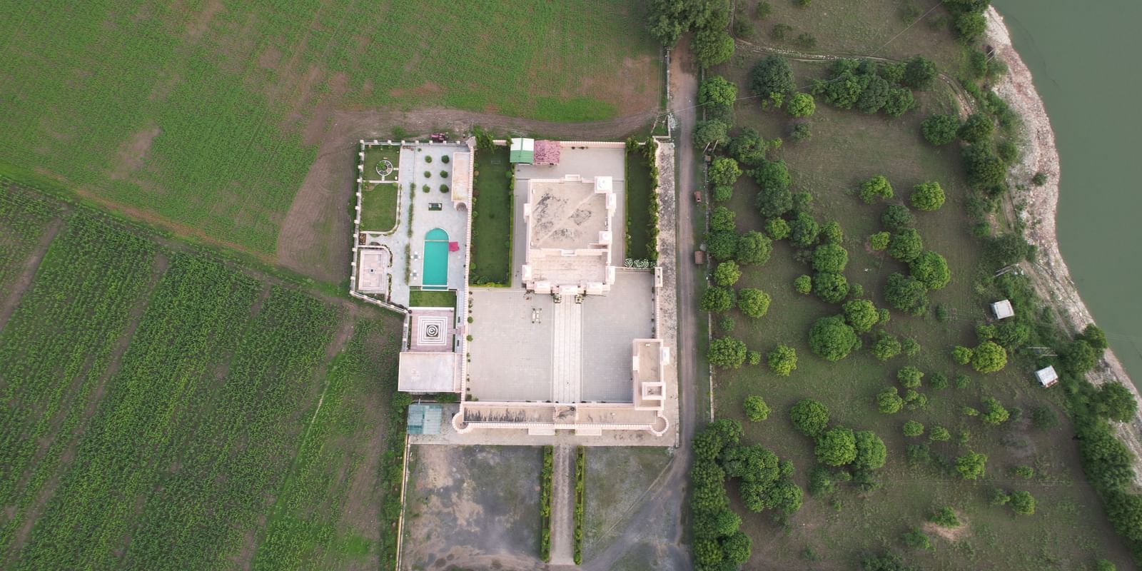 A direct overhead aerial shot of Mahendra Niwas, capturing the intricate layout of the estate, including the buildings, swimming pool, and symmetrical gardens.