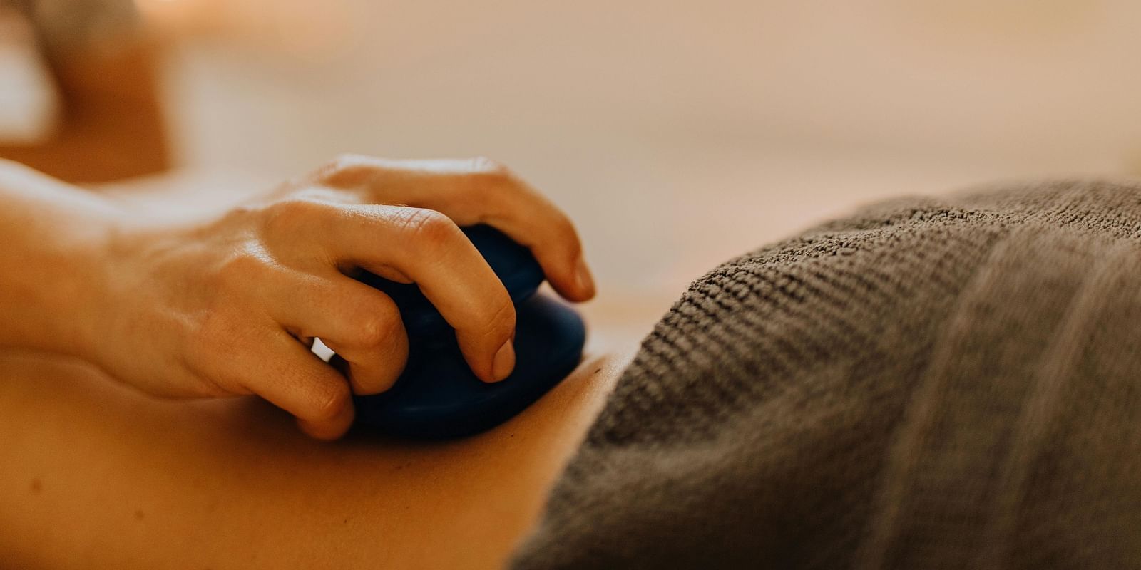 A therapist using a massage tool on a patient's back for deep tissue therapy.