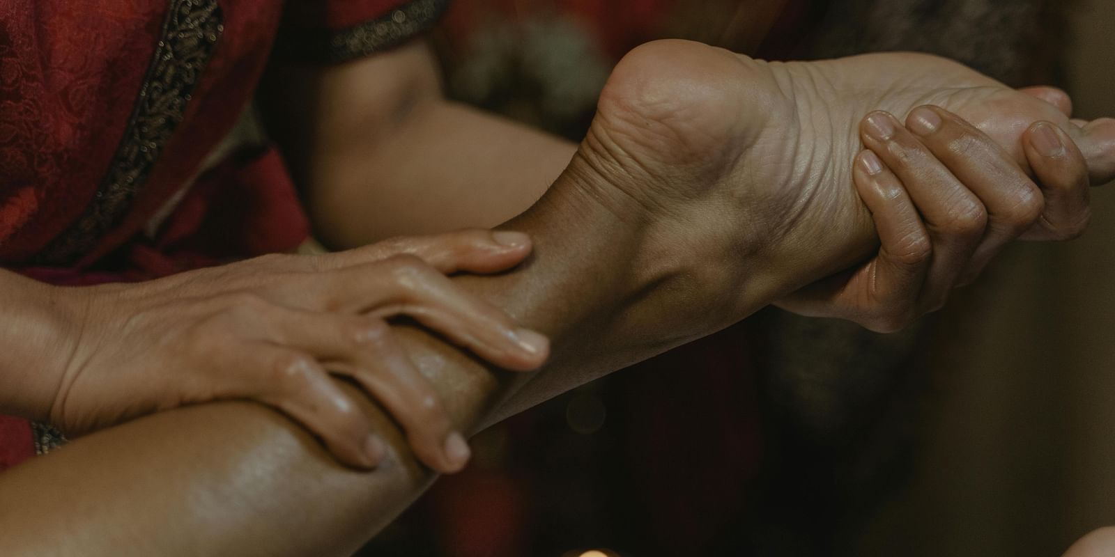 A therapist holding a person's toe with one hand while providing a massage with the other hand.
