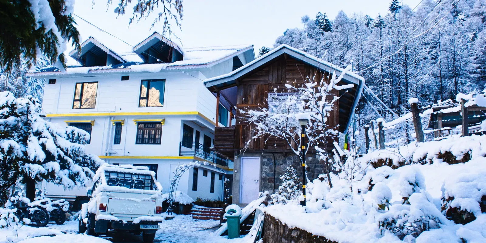  Snow-covered exterior of Avianna Mystique Valley, Lachung with chalet-style buildings and pine forest backdrop.