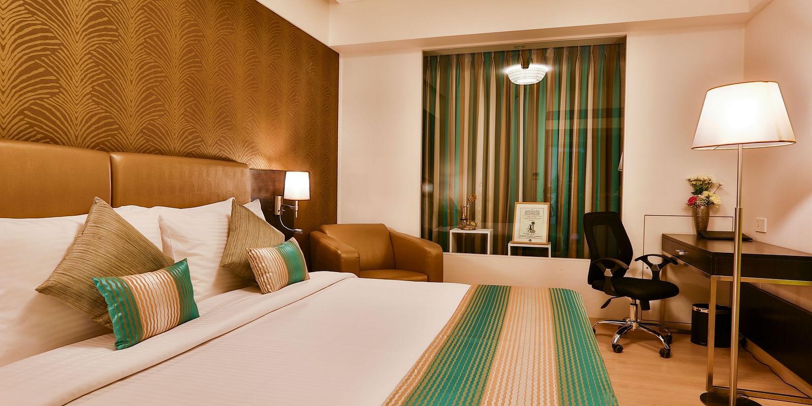 A room with a double bed, a standing lamp and a work desk and chair at T24 Residency, Andheri East, Mumbai
