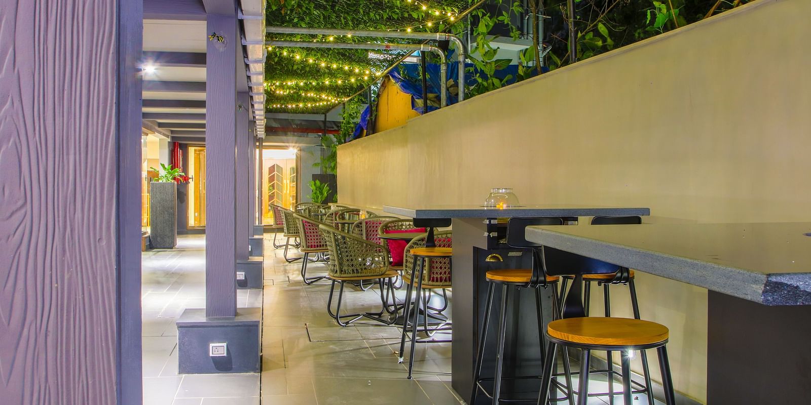 An outdoor dining area with tables and chairs under a wooden pergola  | T24 Retro