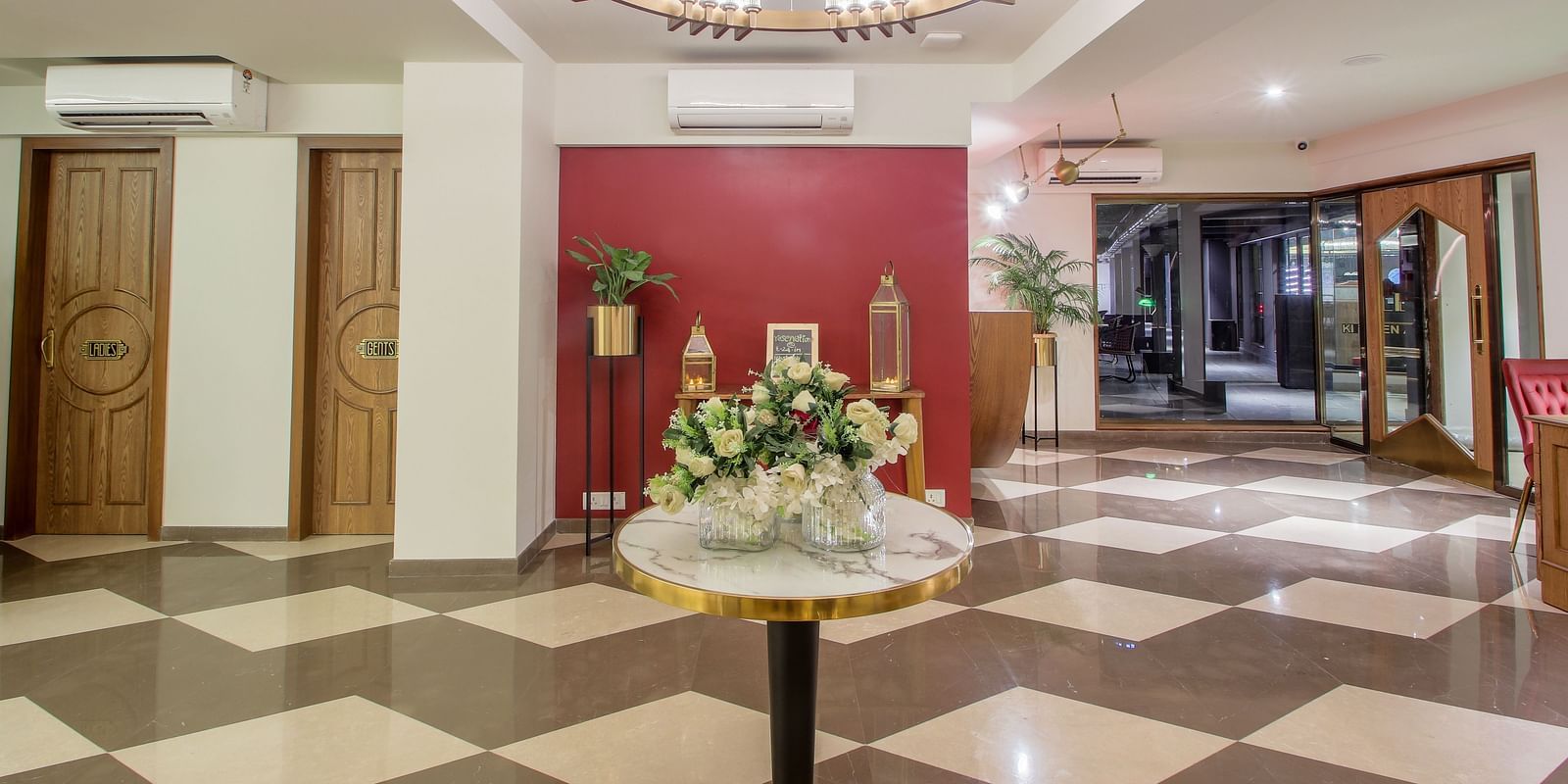 A spacious and elegant hotel lobby with a grand chandelier and a marble-topped table | T24 Retro