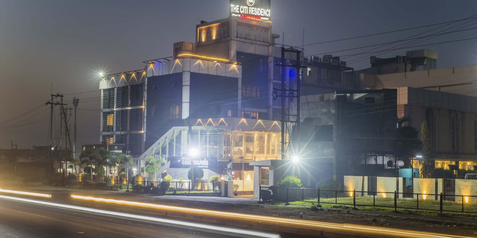 The Citi Residence Hotel, Asansol, illuminated at night with light trails from passing vehicles.