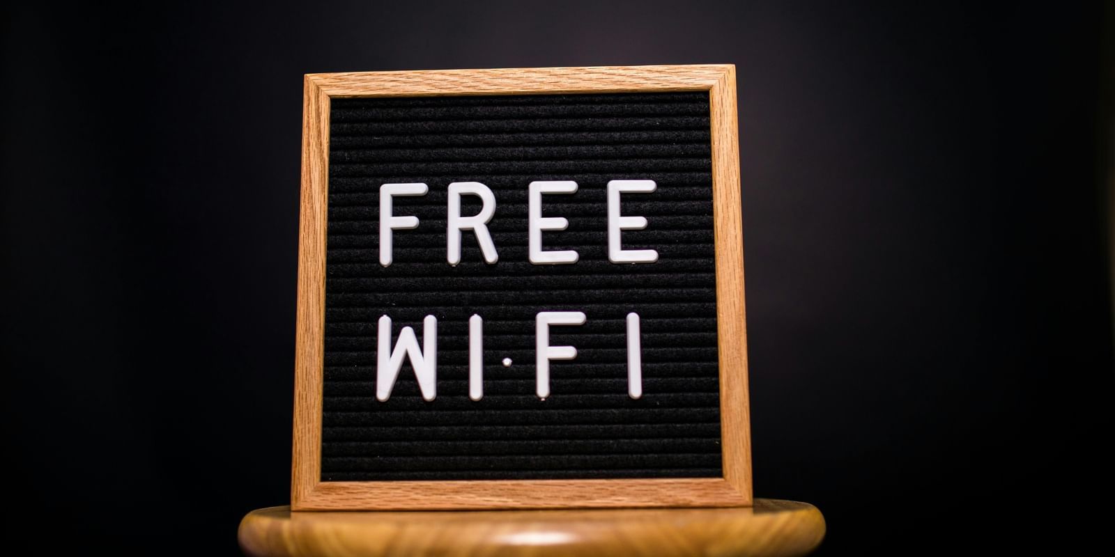A board with FREE WIFI written on it, placed on a wooden stool.
