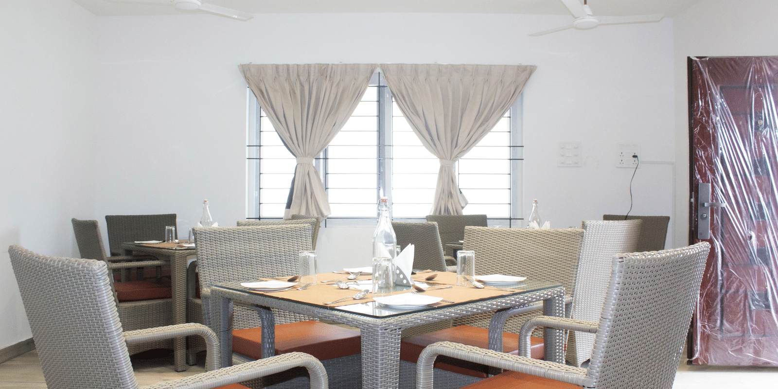 A close-up shot of a well-arranged dining table with 4 chairs kept around it at the Spice and Slice Restaurant at WOW Naturefull Resorts, Yercaud.