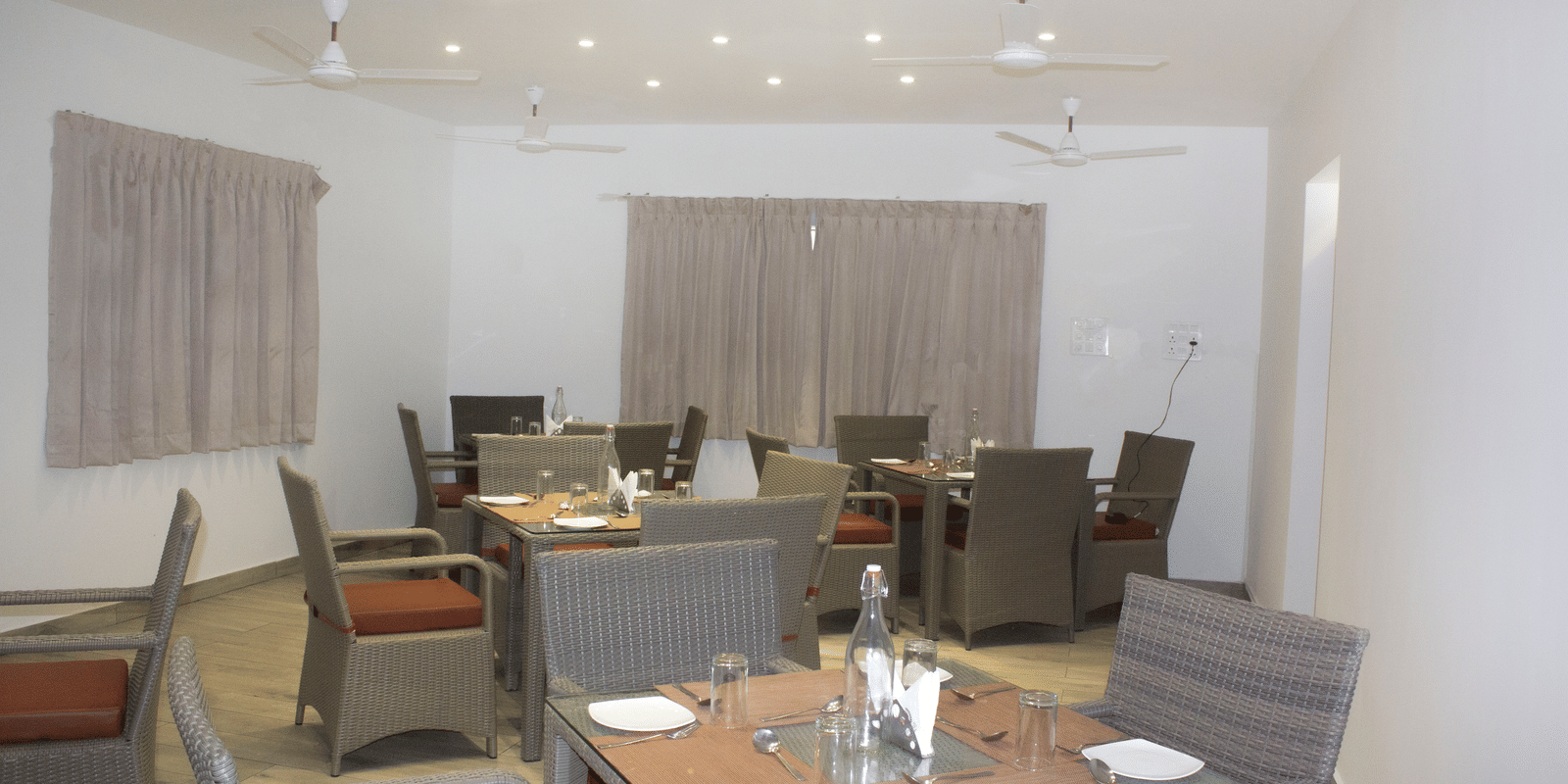 The Spice and Slice Restaurant with dim lighting along with 4 fans hanging from the ceiling at WOW Naturefull Resorts, Yercaud.