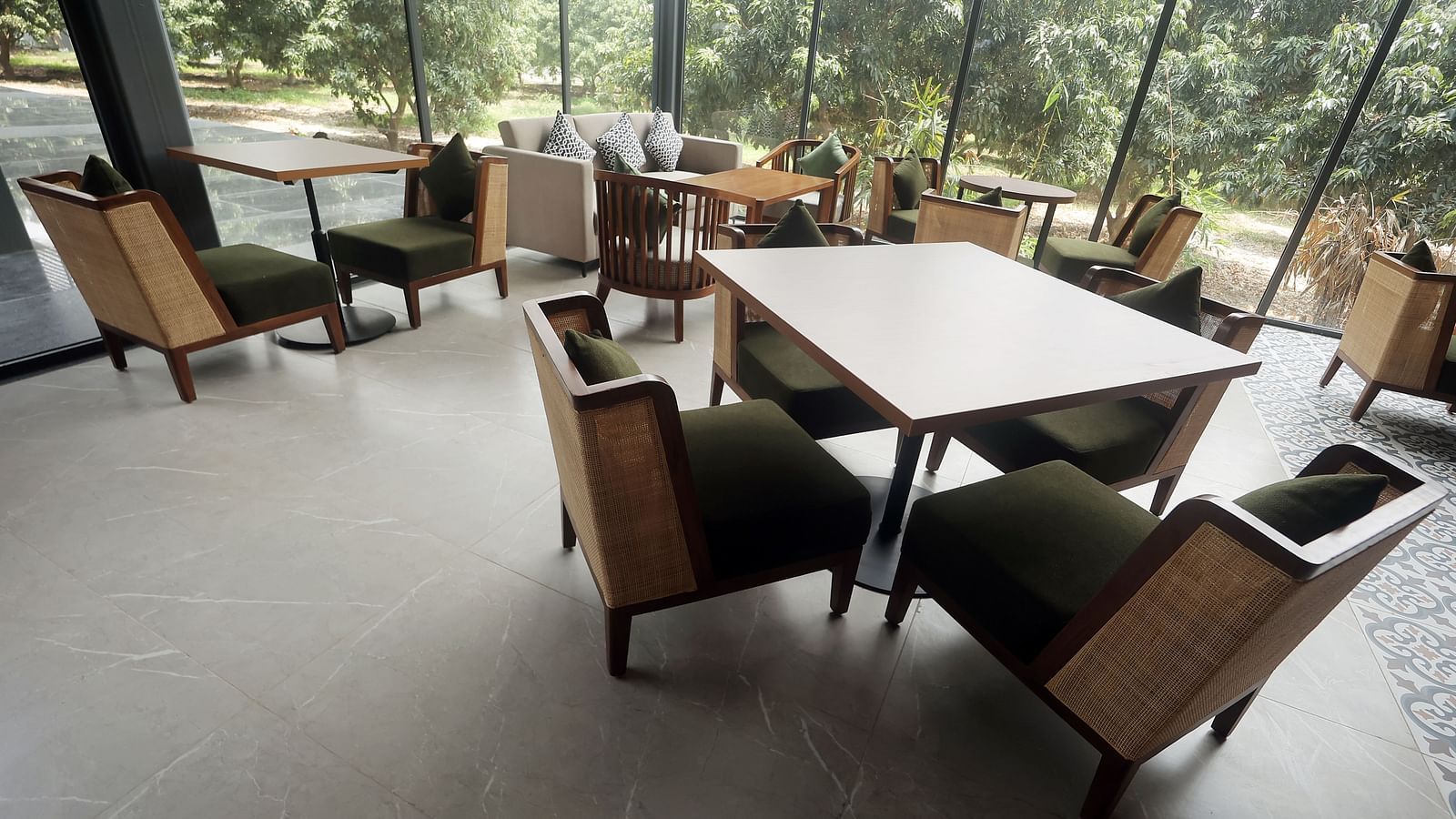 Indoor seating with wooden chairs and orchard views through tall glass panels at Wyndham Garden.