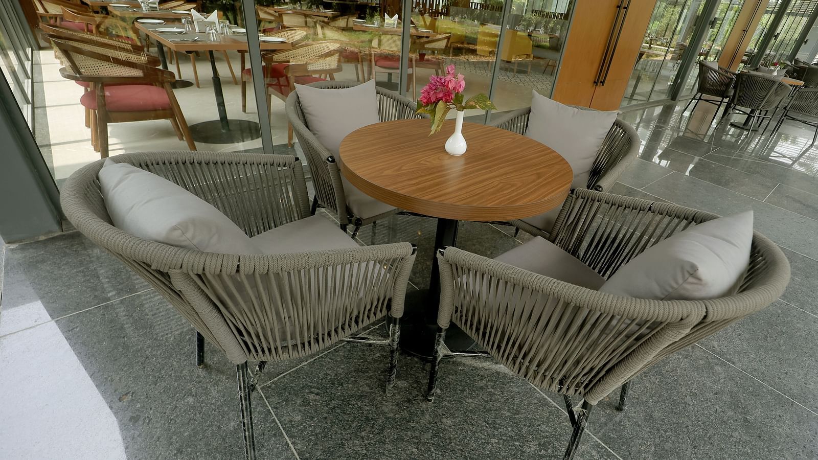 Outdoor-style seating with grey rope chairs and a wooden table, surrounded by natural views at Wyndham Garden.