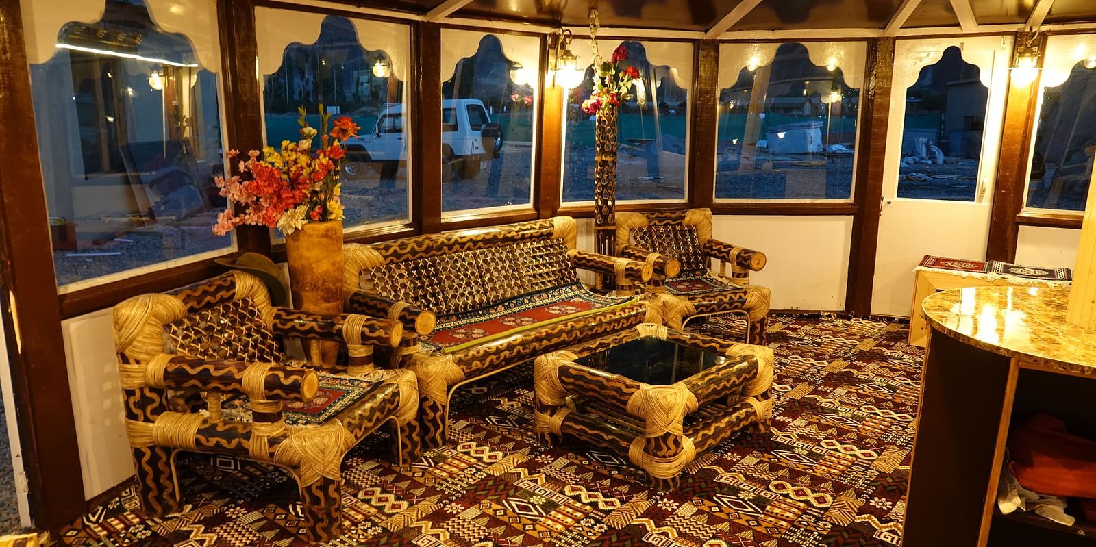 An interior featuring a wooden structure and large arched windows offering outdoor views at White Sands Resort, Ladakh.