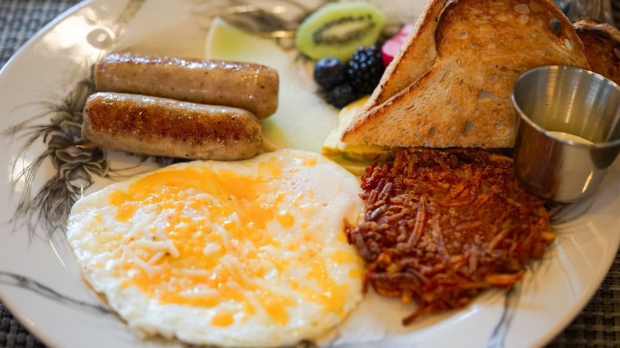 A full breakfast spread featuring sunny-side-up eggs, sausage, crispy hash browns, and a slice of toast - Brewery Gulch Inn & Spa